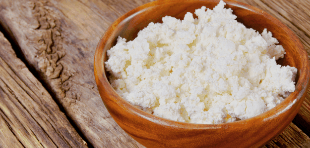 Bowl of cottage cheese on a wooden table.