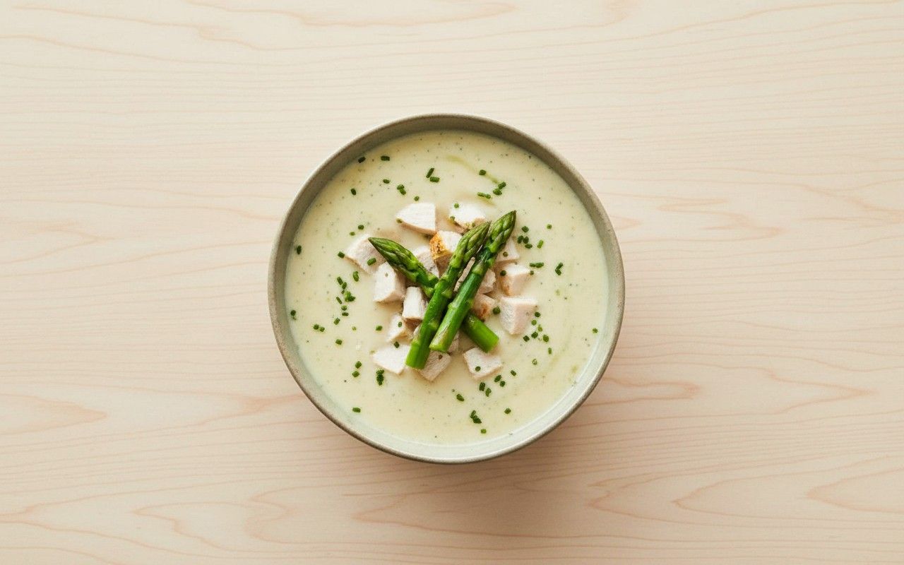 Bowl de crema de espárragos con trozos de pollo y cebollín