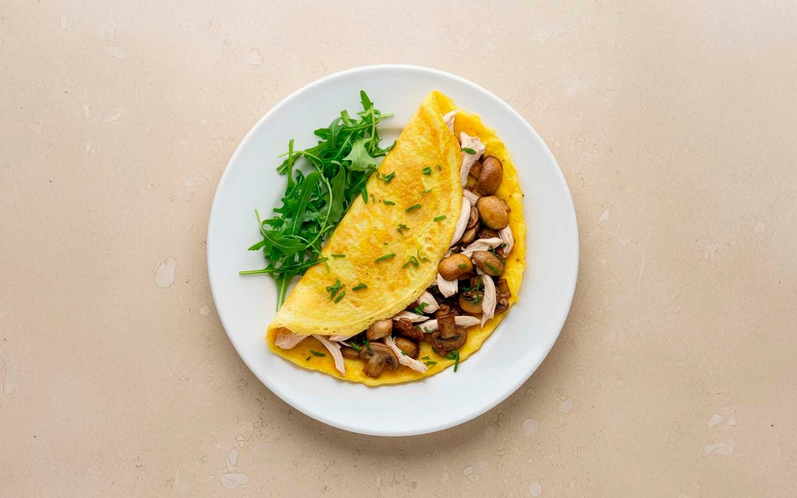Omelette relleno de pollo y champiñones con rúcula fresca