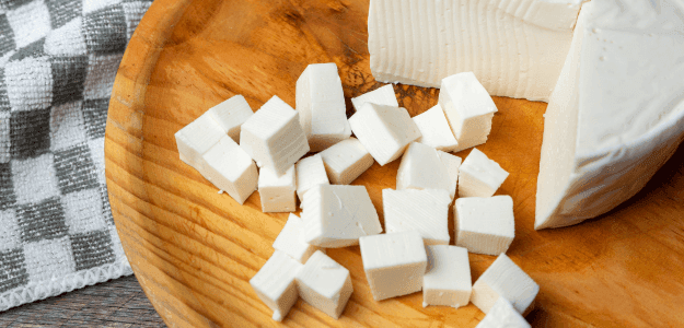 Cubes of panela cheese on a wooden plate.